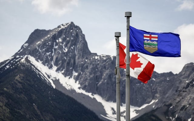 A Canada flag, left, and an Alberta flag flap in the breeze with Wedge Mountain in the background in Kananaskis, Alta., on Monday, June 2, 2025. 