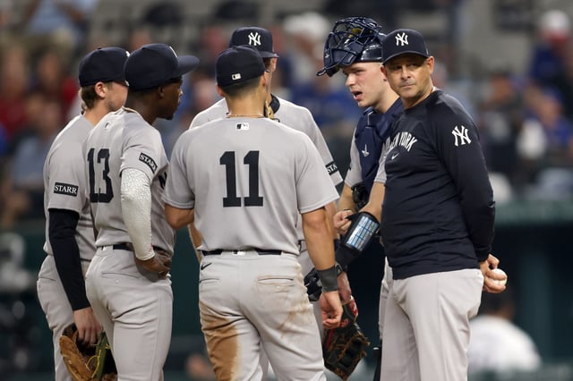 ARLINGTON, TEXAS - AUGUST 05: Manager Aaron Boone #17 of the New York Yankees looks back in the dugout while on the mound during the game against the Texas Rangers at Globe Life Field on August 05, 2025 in Arlington, Texas.
