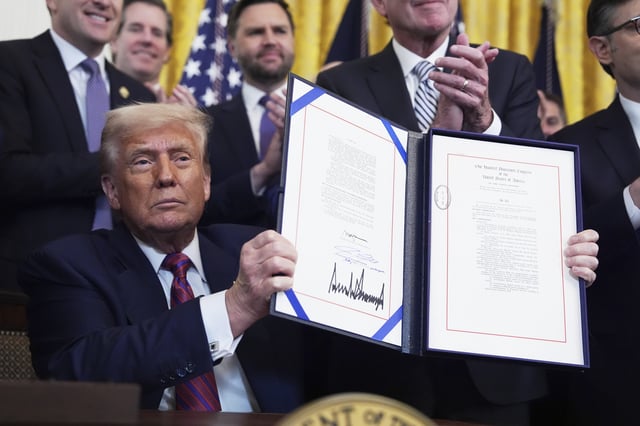 President Donald Trump holds up the signed document after signing the GENIUS Act, a bill that regulates stablecoins, a type of cryptocurrency, in the East Room of the White House, Friday, July 18, 2025, in Washington. (AP Photo/Evan Vucci)