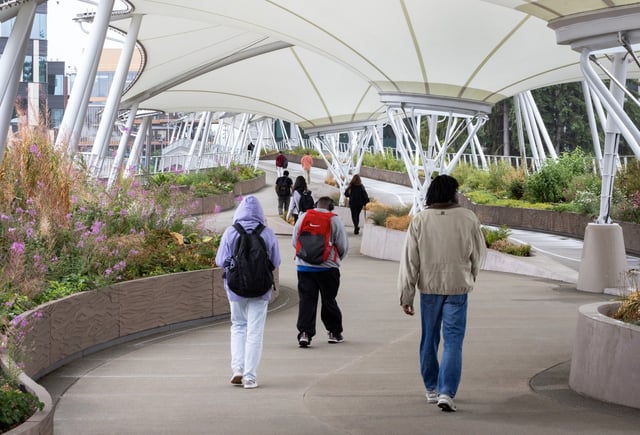 People cross a pedestrian bridge connecting Microsoft&#39;s campuses on Aug. 6, 2025, in Redmond, Washington. Microsoft said it&#39;s looking to refresh its flexible work guidelines, in response to media reports that it may be getting serious about in-person work. (Ken Lambert/The Seattle Times/TNS)
