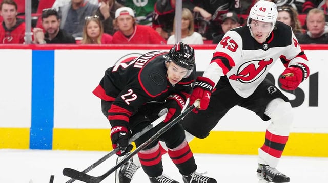 Apr 20, 2025; Raleigh, North Carolina, USA; Carolina Hurricanes center Logan Stankoven (22) battles for the puck against New Jersey Devils defenseman Luke Hughes (43) during the third period of game one of the first round of the 2025 Stanley Cup Playoffs at Lenovo Center. Mandatory Credit: James Guillory-Imagn Images