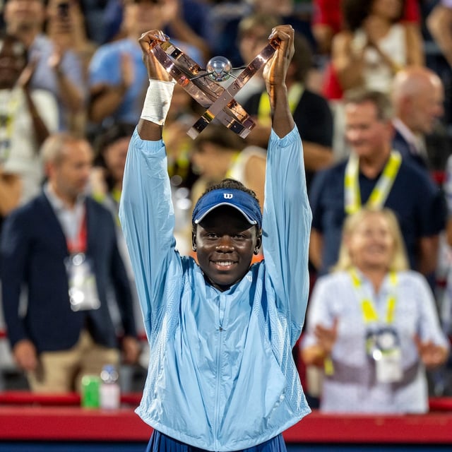 Victoria Mboko of Canada hoists the trophy following her win over Naomi Osaka of Japan during finals tennis action at the National Bank Open in Montreal, Thursday, Aug. 7, 2025. THE CANADIAN PRESS/Christinne Muschi