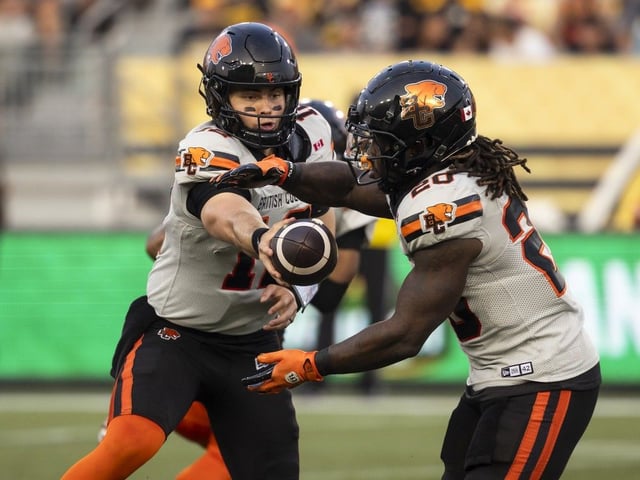  B.C. Lions quarterback Nathan Rourke (12) hands the ball to B.C. Lions’ James Butler (20) during first half CFL football action against the Hamilton Tiger-Cats in Hamilton