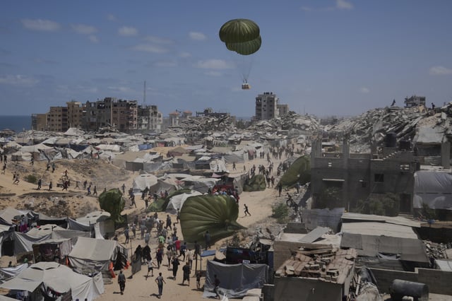 Palestinians rush to collect humanitarian aid airdropped by parachutes into Gaza City, northern Gaza Strip, Thursday, Aug. 7, 2025. (AP Photo/Jehad Alshrafi)