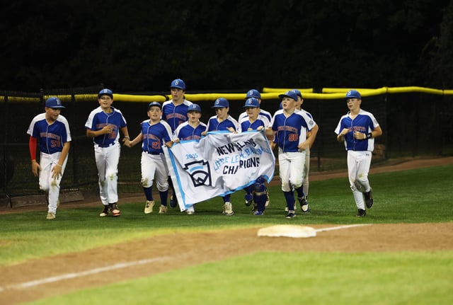 Braintree American Little League players and coaches with the New England banner after a win against New Hampshire in the Little League New England Regional championship on Thursday, Aug. 7, 2025 in Bristol, CT.