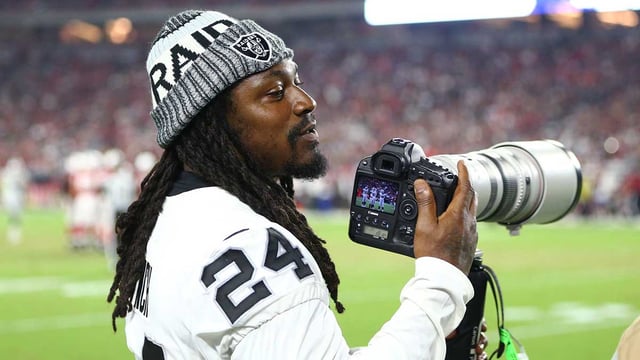 Aug 12, 2017; Glendale, AZ, USA; Oakland Raiders running back Marshawn Lynch takes pictures with a Canon camera on the sidelines against the Arizona Cardinals at University of Phoenix Stadium. Mandatory Credit: Mark J. Rebilas-Imagn Images.