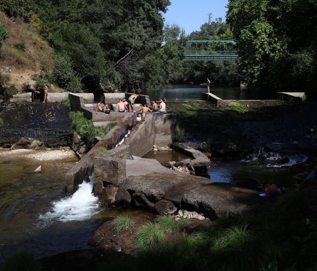 Bañistas en la presa de Monte Porreiro, donde se observa la caída del caudal.