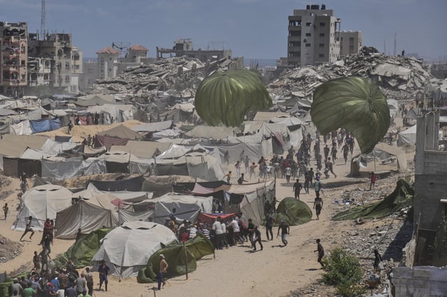 Palestinians rush to collect humanitarian aid airdropped by parachutes into Gaza City, northern Gaza Strip, Thursday, Aug. 7, 2025. (AP Photo/Jehad Alshrafi)