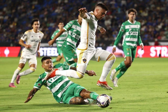 Galaxy forward Gabriel Pec, top, jumps to avoid a slide tackle by Club Santos Laguna defender Bruno Amione (2) during the first half of a Leagues Cup match at Dignity Health Sports Park in Carson, Calif. on Thursday, Aug. 7, 2025.  (Photo by Raul Romero Jr., Contributing Photographer)