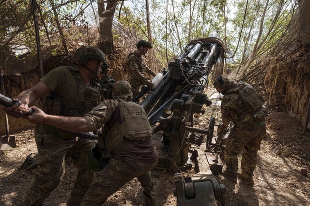 Ukrainian servicemen of the 148th artillery brigade load ammunition into a M777 howitzer before firing towards Russian positions at the frontline in Zaporizhzhia region, Ukraine, on Thursday, Aug. 7, 2025. (AP Photo/Evgeniy Maloletka)