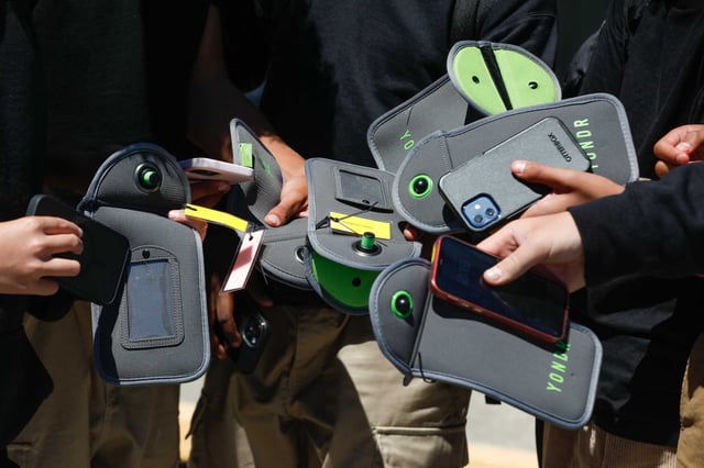 Houston ISD and more than 5 million of Texas&#39; public and charter school students will return to school screen-free this school year as a new cellphone ban comes into effect statewide. A student uses their phone after unlocking the pouch that secures it from use during the school day at Bayside Academy in 2024 in San Mateo, Calif. 