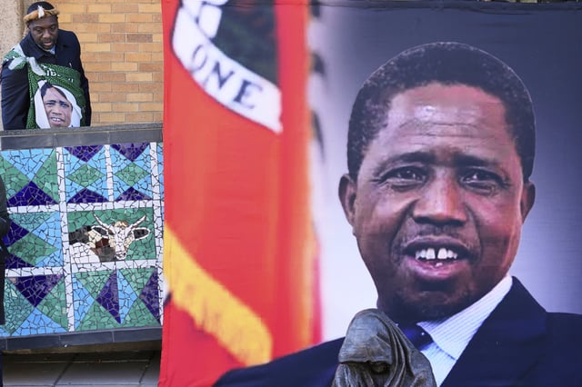FILE -A supporter arrives for a Mass for former Zambian President Edgar Lungu, shown in a banner at right, at the Cathedral of Christ the King in Johannesburg, South Africa, June 25, 2025. (AP Photo/Themba Hadebe), File)