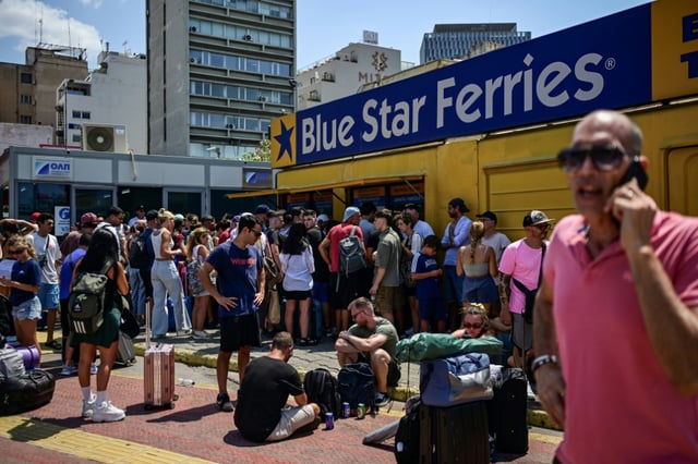 Des personnes patientent devant les guichets au port du Pirée, près d'Athènes, le 8 août 2025