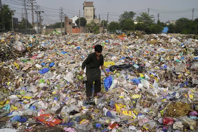 A scavenger collects recyclable items including plastic from a dump site in Lahore, Pakistan, Thursday, Aug. 7, 2025. (AP Photo/K.M. Chaudary)