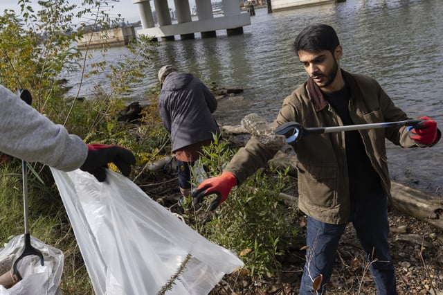 FILE - Volunteers collect trash and plastic waste during a park cleanup on Nov. 15, 2023, at Anacostia Park in Washington. (AP Photo/Tom Brenner, File)