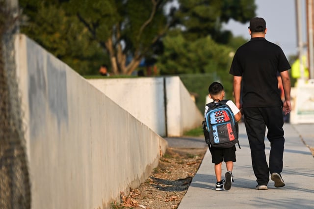 A father and son hold hand as they walk into McKinley Elementary School for the first day of the 2025-2026 school year in Colton on Monday, Aug. 4, 2025. (Photo by Anjali Sharif-Paul, The Sun/SCNG)