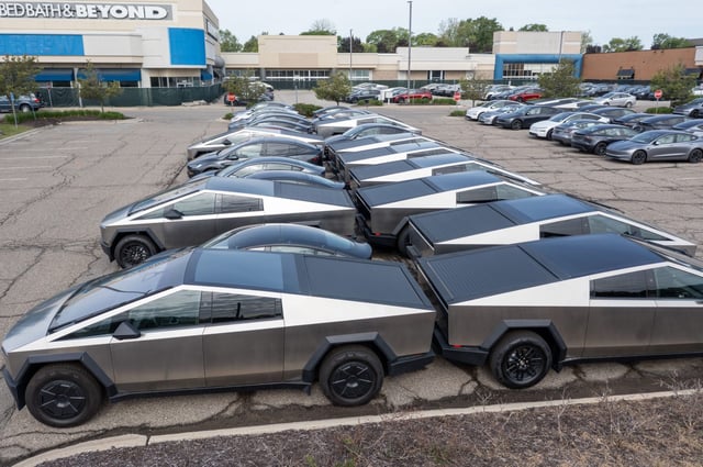 Many dozens of unsold Tesla electric vehicles, including Cybertrucks, are stored in the parking lot of a closed shopping center in suburban Detroit.