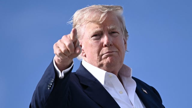 US President Donald Trump points as he boards Air Force One at RAF Lossiemouth, north-east Scotland.