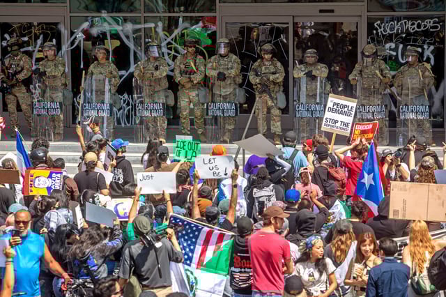 Demonstrators holding signs and flags face California National Guard members standing guard outside the Federal Building as they protest in response to federal immigration operations in Los Angeles, on June 9, 2025. 