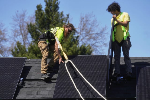 Theodore Tanczuk, left, and Brayan Santos, right, of solar installer YellowLite, work to put panels on a home in Lakewood, Ohio, Wednesday, April 16, 2025. (AP Photo/Sue Ogrocki)