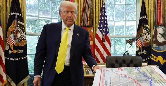 U.S. President Donald Trump holds a board, as he makes an announcement on the economy, in the Oval Office at the White House in Washington, D.C., U.S., August 7, 2025. REUTERS/Jonathan Ernst