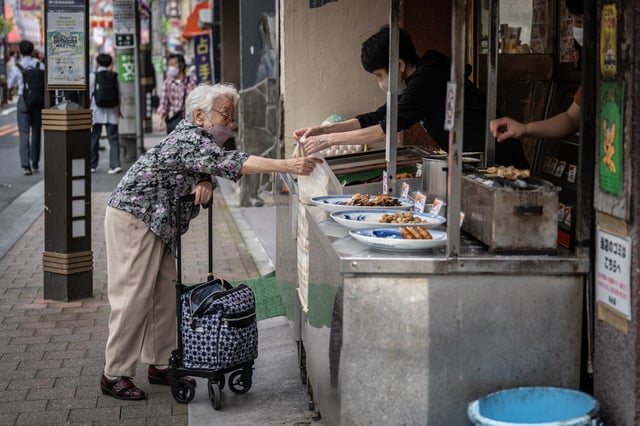 An elderly woman shops at a grilled chicken shop in the Sugamo area of Tokyo on May 22, 2024.