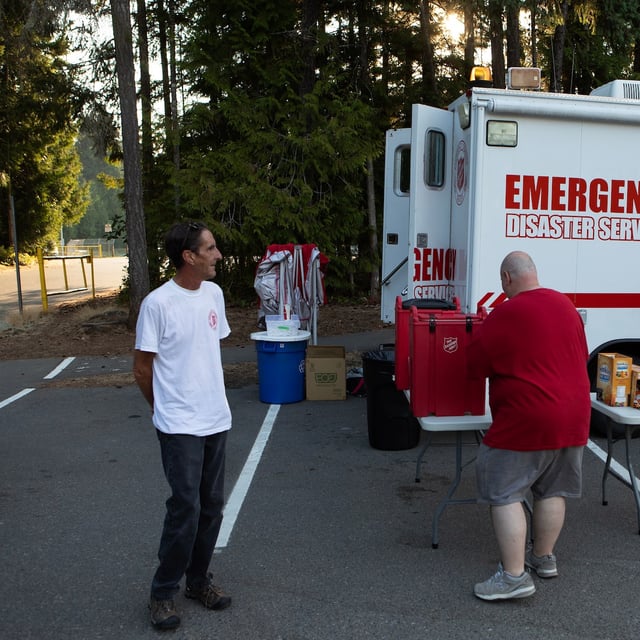 An evacuees pours a coffee at the Salvation Army's Emergency Disaster Services as volunteers await to provide food and other services for evacuees while in the parking lot of the Qualicum Civic Centre in Qualicum Beach, B.C., Sunday, Aug. 3, 2025. THE CANADIAN PRESS/Chad Hipolito