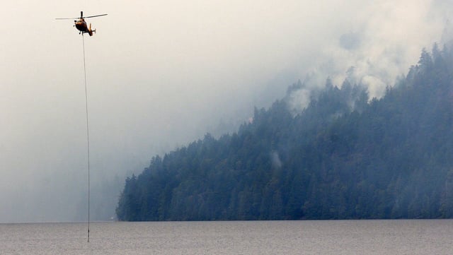 A helicopter refills a bucket of water at Cameron Lake off Highway 4 where the Wesley Ridge wildfire continues to burn out-of-control near Coombs, B.C., on Sunday, August 3, 2025. THE CANADIAN PRESS/Chad Hipolito