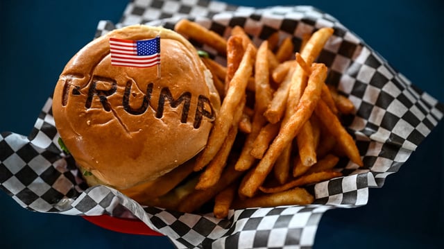 TOPSHOT - A burger is seen at Trump Burger restaurant, in Bellville, Texas, on April 19, 2025. It is lunchtime at a Texas eatery called Trump Burger and diners are enjoying fast food and the frenetic first 100 days of their president&#39;s second term. Trump is everywhere in this joint with a dozen tables -- in cardboard cutouts of the man eking out his trademark forced smile, on banners from the 2024 campaign, and on hats and T-shirts displayed for sale. It is a franchise of a company with four such Trump-themed outlets in Texas and no equal anywhere else in America. The chain is not linked to the Trump Organization.