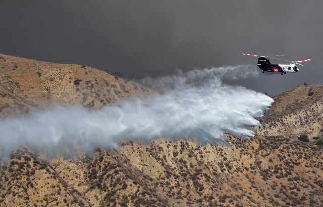 A helicopter drops water on the Canyon Fire, which started southeast of Lake Piru around 1:30 p.m. on Aug. 7, 2025, in a remote area in the mountains between Piru and Interstate 5.
