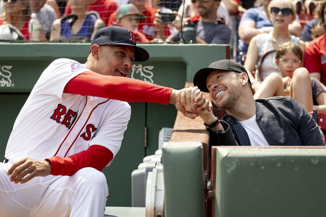 BOSTON, MASSACHUSETTS - AUGUST 3: Manager Alex Cora #13 of the Boston Red Sox shakes hands with Donnie Wahlberg before a game against the Houston Astros on August 3, 2025 at Fenway Park in Boston, Massachusetts.