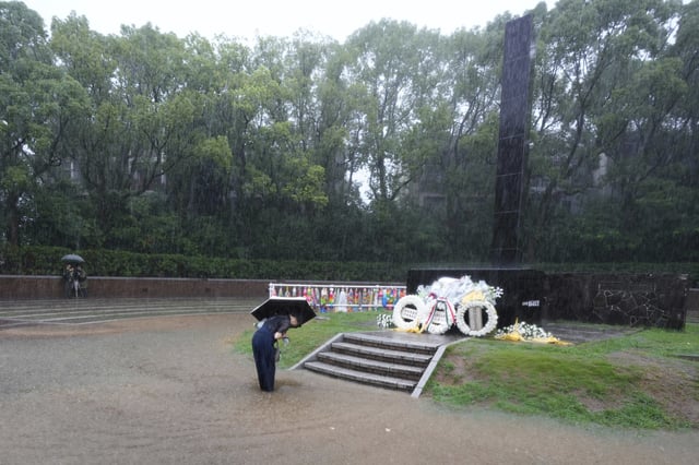 People bows to pray in the rain, at at the Atomic Bomb Hypocenter Park, ahead of a public ceremony to commemorate the 80th anniversary of the day an atomic bomb was dropped on Nagasaki, in Nagasaki, Japan Saturday, Aug. 9, 2025.(AP Photo/Eugene Hoshiko)