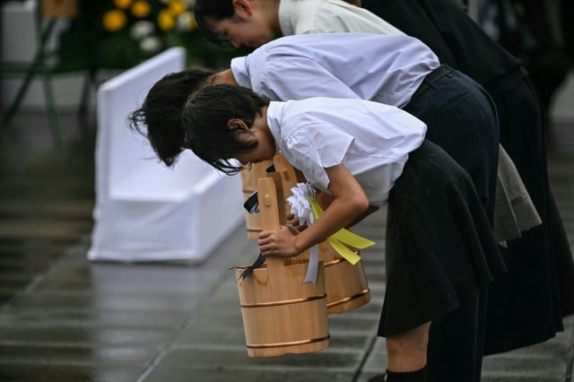 Des élèves réalisent un rituel avec des seaux d'eau comme offrandes, le 9 août 2025 à Nagasaki pour marquer les 80 ans du bombardement atomique de la ville