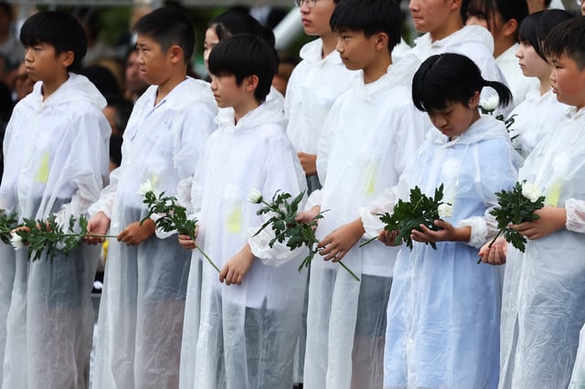 Children hold flowers during a ceremony commemorating the 80th anniversary of the bombing of the city, at Nagasaki's Peace Park in Nagasaki, southwestern Japan, August 9, 2025.  REUTERS/Issei Kato