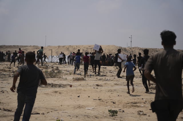 Palestinians collect humanitarian aid packages from the United Arab Emirates after they were airdropped into Deir al-Balah, in central Gaza Strip, Saturday, Aug. 9, 2025. (AP Photo/Abdel Kareem Hana)