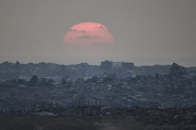 The sun sets behind buildings that were destroyed during the Israeli ground and air operations stand in the northern Gaza Strip as seen from southern Israel, Friday, Aug. 8, 2025. (AP Photo/Leo Correa)