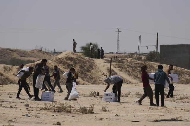 Palestinians collect humanitarian aid packages from the United Arab Emirates after they were airdropped into Deir al-Balah, in central Gaza Strip, Saturday, Aug. 9, 2025. (AP Photo/Abdel Kareem Hana)