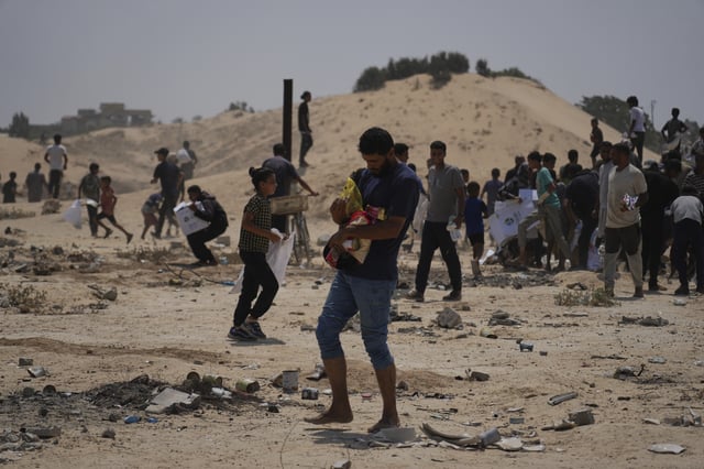 Palestinians collect humanitarian aid packages from the United Arab Emirates after they were airdropped into Deir al-Balah, in central Gaza Strip, Saturday, Aug. 9, 2025. (AP Photo/Abdel Kareem Hana)
