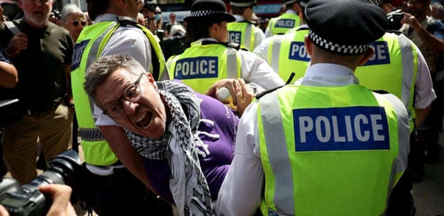 Un manifestant est emmené par des policiers lors d'une manifestation « Lift The Ban » (Lève l'interdiction) en soutien au groupe interdit Palestine Action, qui réclame la levée de l'interdiction récemment imposée, sur Parliament Square, dans le centre de Londres, le 9 août 2025