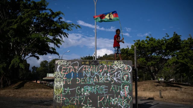 Pendant les émeutes de 2024, une jeune fille brandit un drapeau kanak, dans le quartier de Montravel à Nouméa, le 24 septembre, date de la prise de possession du territoire par la France.