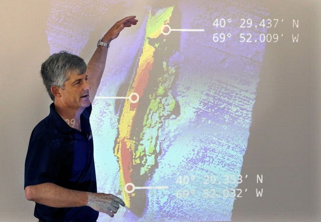 OceanGate CEO and co-founder Stockton Rush speaks in front of a projected image of the wreckage of the ocean liner SS Andrea Doria on June 13, 2016, in Boston.