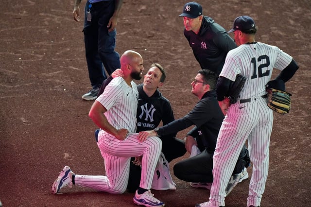 New York Yankees manager Aaron Boone and Trent Grisham (12) watch as trainers check on Amed Rosario during the 10th inning of a baseball game against the Houston Astros Friday, Aug. 8, 2025, in New York. (AP Photo/Frank Franklin II)