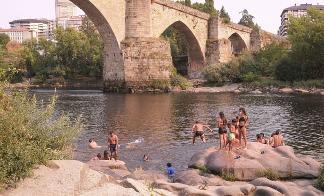 Varias personas hacen frente a la ola de calor en la orilla del Miño. |  Roi Cruz
