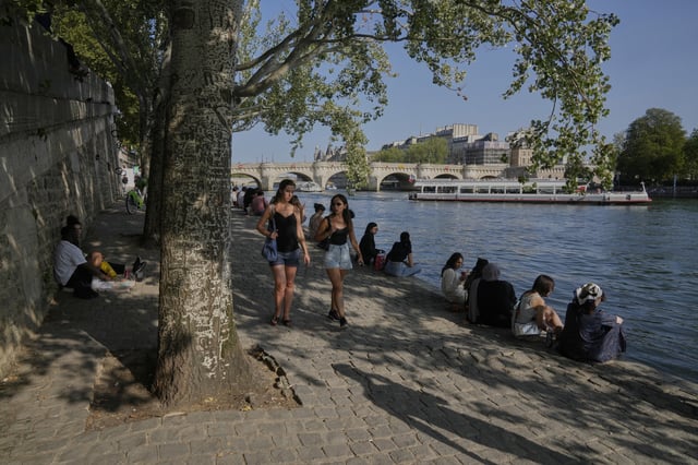 People sit in the shade along the Seine river during a sunny day in Paris, Sunday, Aug. 10, 2025. (AP Photo/Michel Euler)