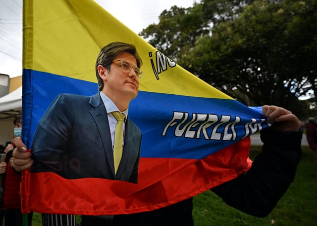 A woman holds a Colombian flag with the image of Colombian presidential candidate Miguel Uribe during a mass for his health in Bogota on June 21, 2025.