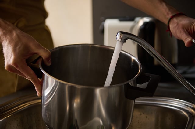 File photo: a man fills a saucepan with water to boil.