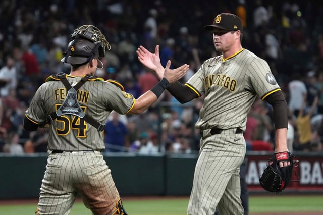 San Diego Padres catcher Freddy Fermin (54) and pitcher Mason Miller celebrate after defeating the Arizona Diamondbacks in a baseball game, Wednesday, Aug. 6, 2025, in Phoenix. (AP Photo/Rick Scuteri)