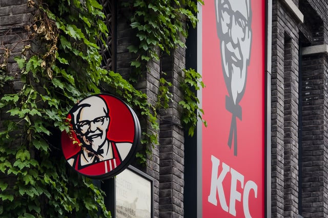 The logo of Kentucky Fried Chicken (KFC) is seen mounted on a vine-covered traditional-style brick building, blending global fast food branding with localized architectural aesthetics, on May 07, 2025 in Chongqing, China.
