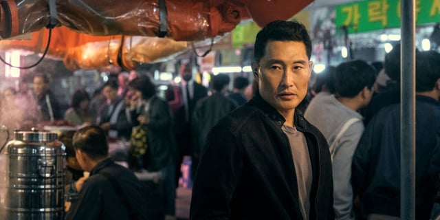 Daniel Dae Kim as David standing in a market in Butterfly.