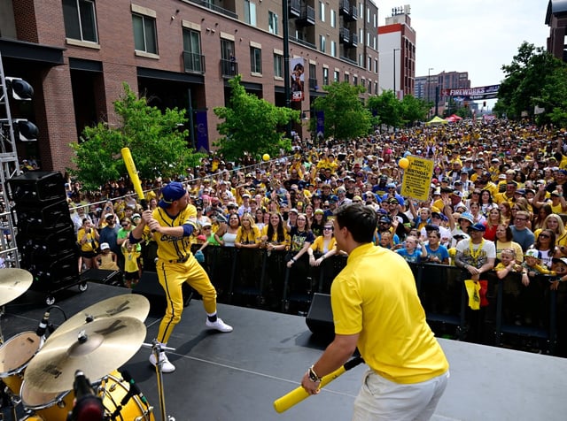 Savannah Bananas director of entertainment, Zack Frongillo, left, hits foam balls out into the crowd during the Before the Peel Show on Blake St. ahead of the game between the Savannah Bananas and The Firefighters at Coors Field in Denver on Saturday, Aug. 9, 2025. (Photo by Andy Cross/The Denver Post)